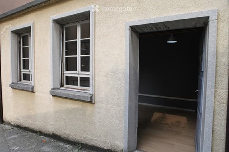 Empty room with wooden floor, visible through an open doorway. The room has bare walls and no furniture or equipment.