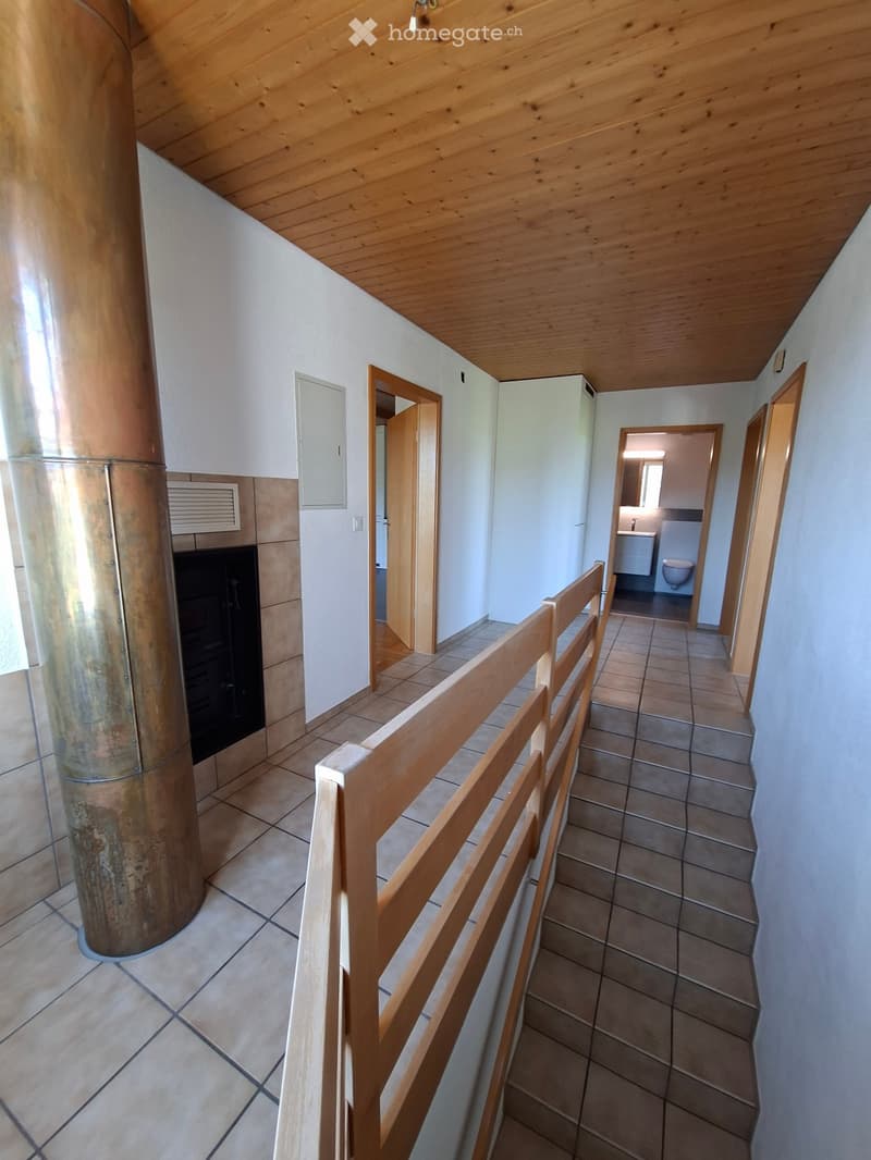 Hallway with tiled floor, wooden railing, and visible bathroom at the end.