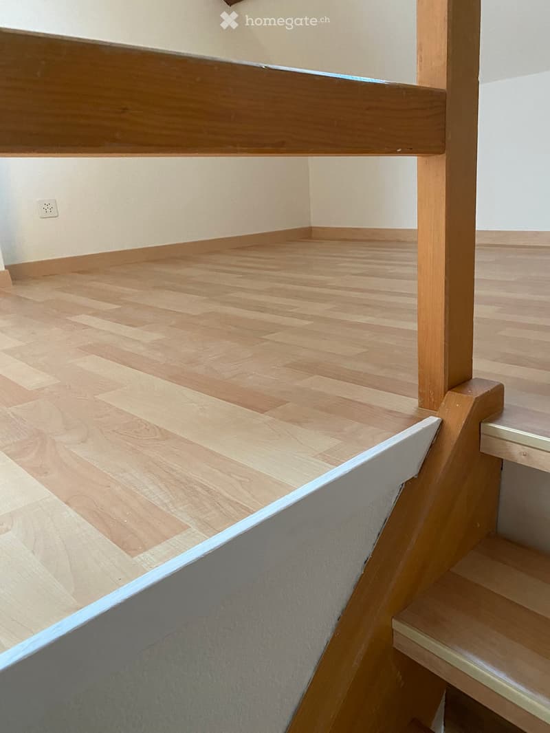 Empty hallway with wooden flooring and a staircase featuring wooden railings and steps.