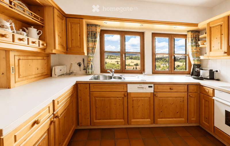 Bright kitchen with wooden cabinets, white countertops, and a large window offering a scenic view. Includes a sink, dishwasher, oven, coffee maker, and toaster.