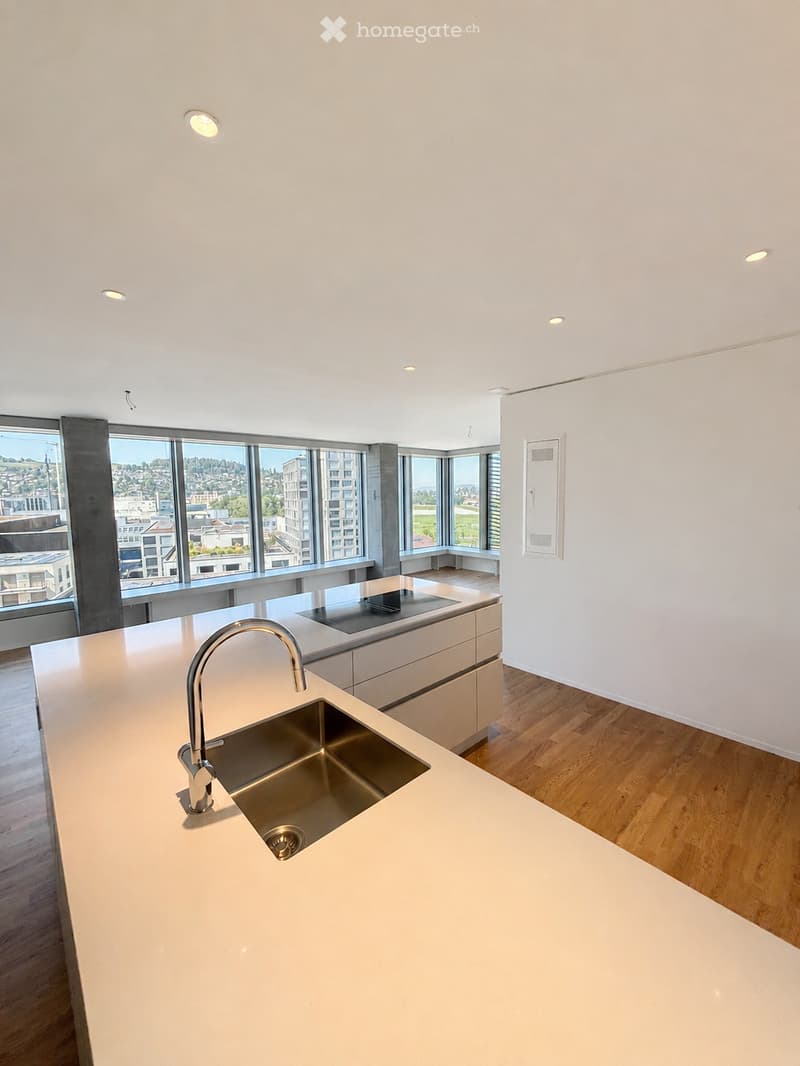 Modern kitchen with white countertops, stainless steel sink and faucet, built-in stove, and large windows offering a city view.