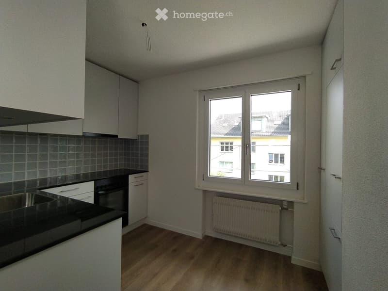 modern kitchen with black countertop, white cabinets, and window with view