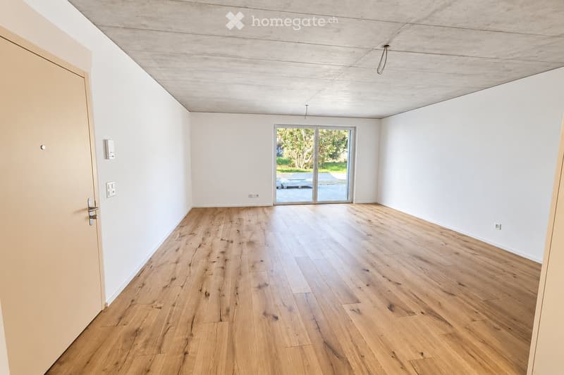 Empty room with light wooden flooring, white walls, and a large sliding glass door leading to an outdoor area.