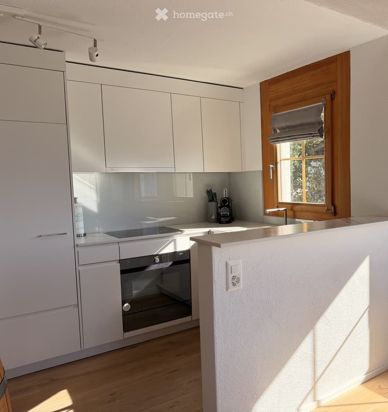 Modern kitchen with white cabinets, stainless steel appliances, and a central island with a sink and countertop.