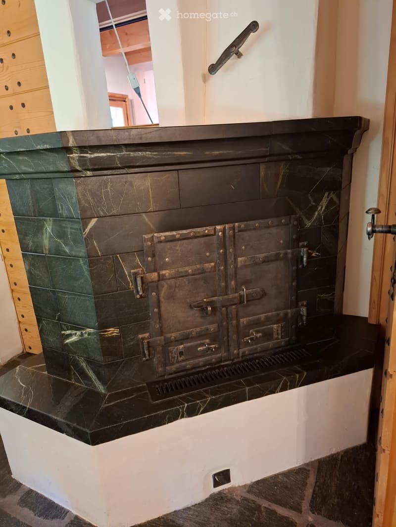 {"type": "Fireplace", "objects": [], "description": "A black marble fireplace with intricate metalwork and a green marble surround, set against white walls with wooden trim visible on the left side.", "localized_descriptions": {"EN": "A black marble firep