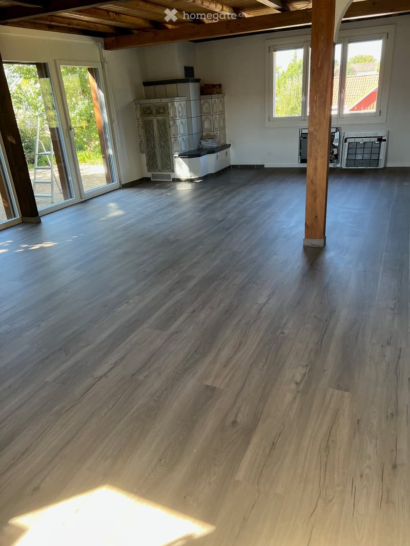 Empty room with wooden flooring, large windows, and a sliding glass door leading to an outdoor area. No furniture or equipment is present.