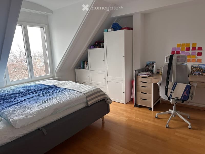 Bedroom with bed, desk, chair, closet, window with view, white walls, wooden floor.