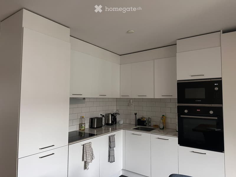 white cabinetry, gas stove, sink, white countertops, modern appliances, power outlet, white tiled backsplash