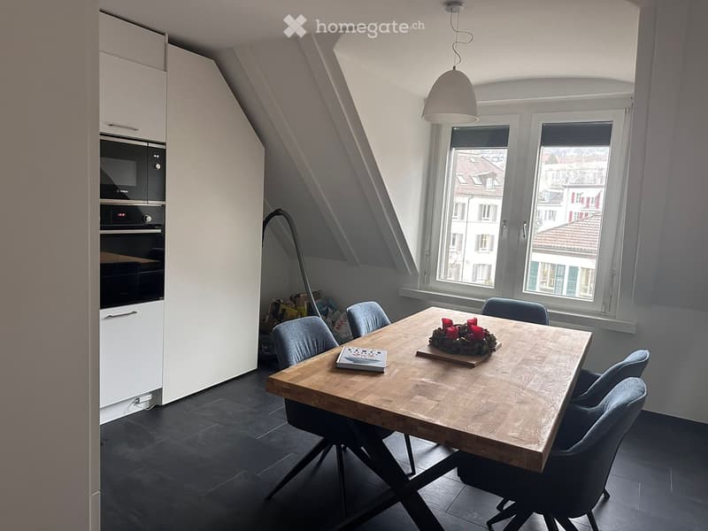 dining area with wooden table, modern blue chairs, white cupboards with microwave, black tile floor, pendant lamp, large window