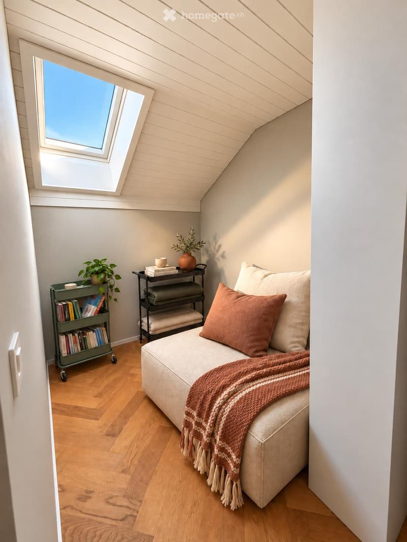 Cozy attic room with slanted ceilings, wooden floors, a sofa with a throw blanket and pillows, a side table with books and a potted plant, and a small bookshelf with books and a cup.