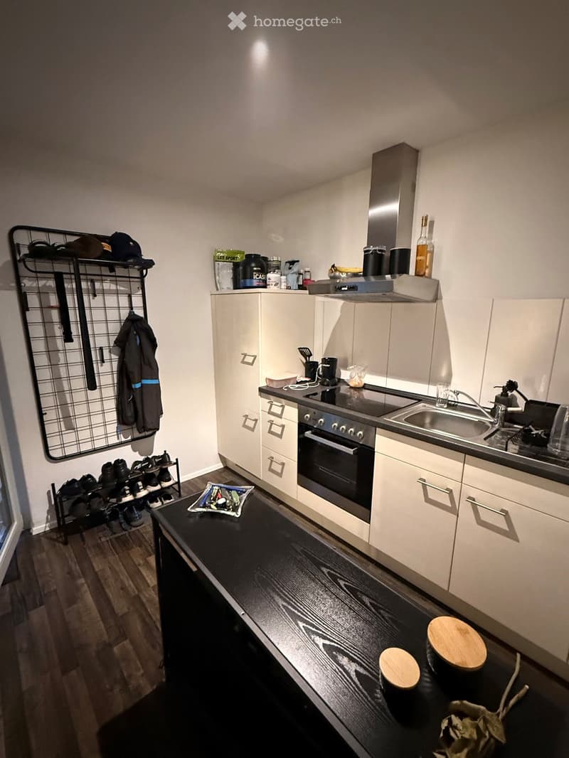 Modern kitchen with white cabinets, black countertops, and stainless steel appliances. Includes an oven, sink, and various kitchen items on the counter.