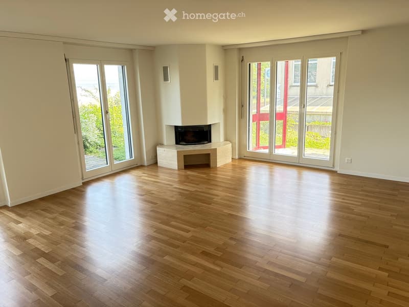 Empty room with wooden flooring, large glass doors, and a built-in fireplace.