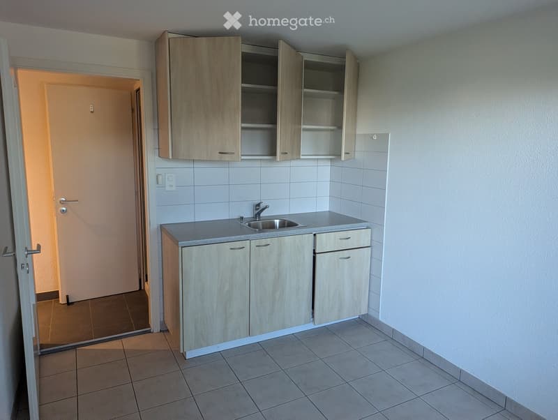 Empty kitchen with light wood cabinets, a sink, and tiled flooring.