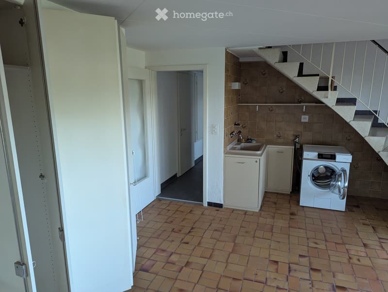 Laundry room with tiled floor, white washing machine, sink, and small cabinet.