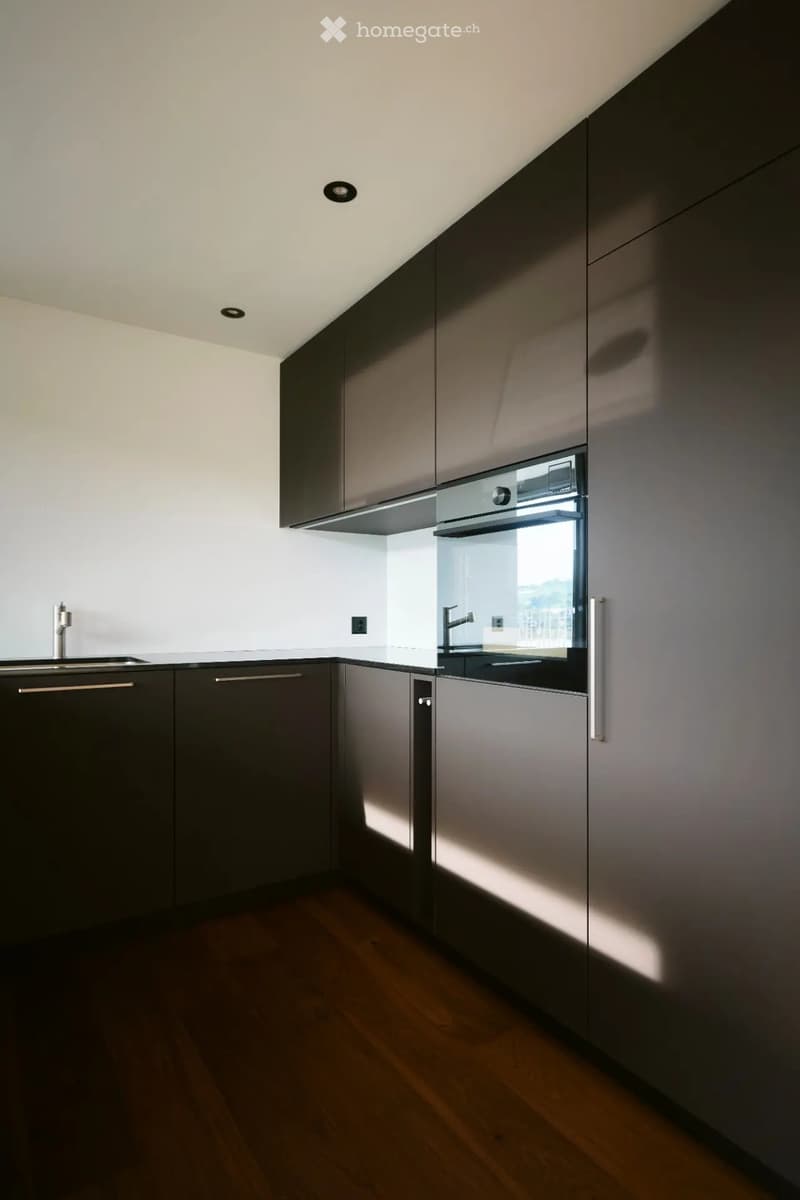 Modern kitchen with dark grey cabinets, stainless steel oven, and a sleek sink with a modern faucet.