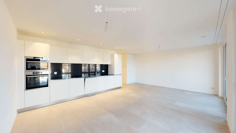 Modern kitchen with white cabinets, stainless steel oven, and light wooden flooring.