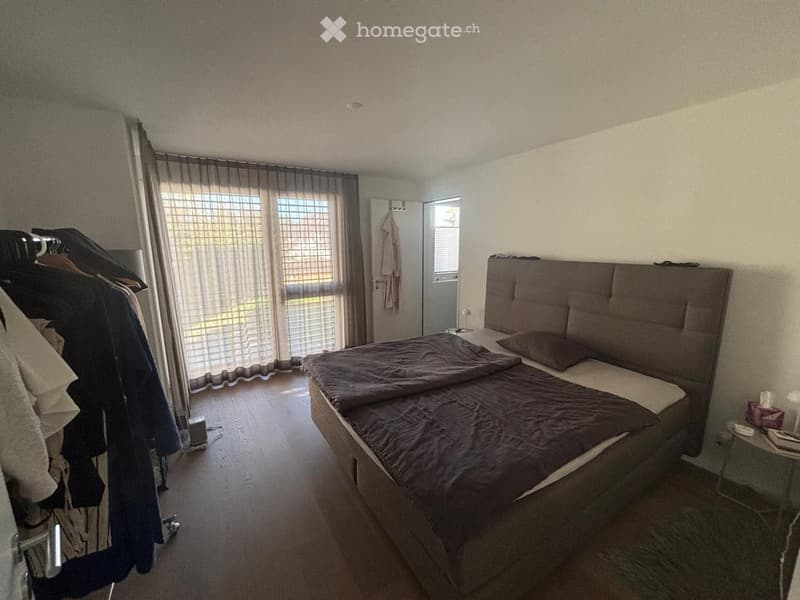 Bedroom with a large bed, nightstand, wardrobe, and window with curtains.