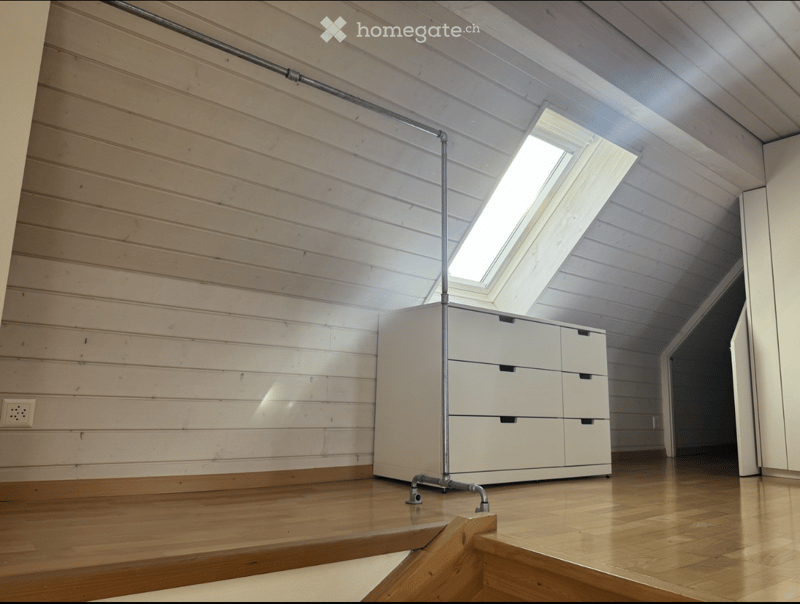 Minimalist room with wooden walls and floor, white cabinet, skylight window, and exposed metal pipe structure.