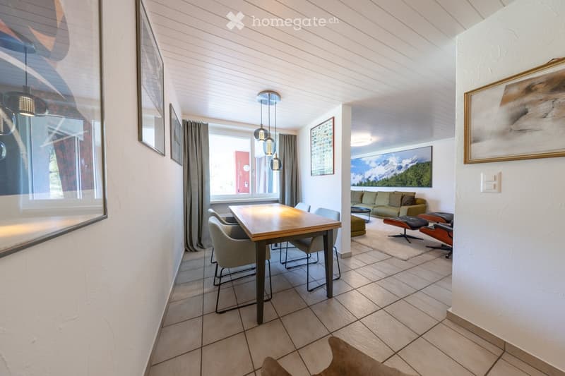 Open-plan living and dining area with modern furniture, pendant lights, and large windows with views.