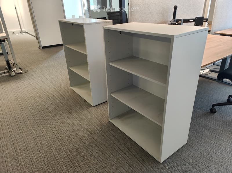 Office space with white shelving units and a black office chair visible in the background.