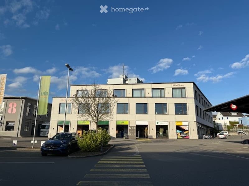 Commercial building, multiple shops on the ground floor, several windows, street parking in front