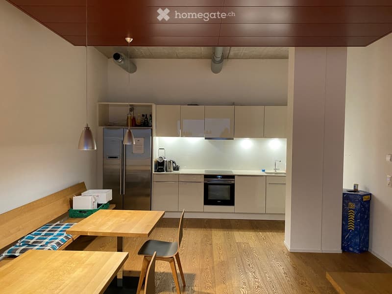 Stainless steel fridge, white cabinets, granite countertops, integrated oven, sink with faucet, wooden tables, and a wooden bench with cushions.