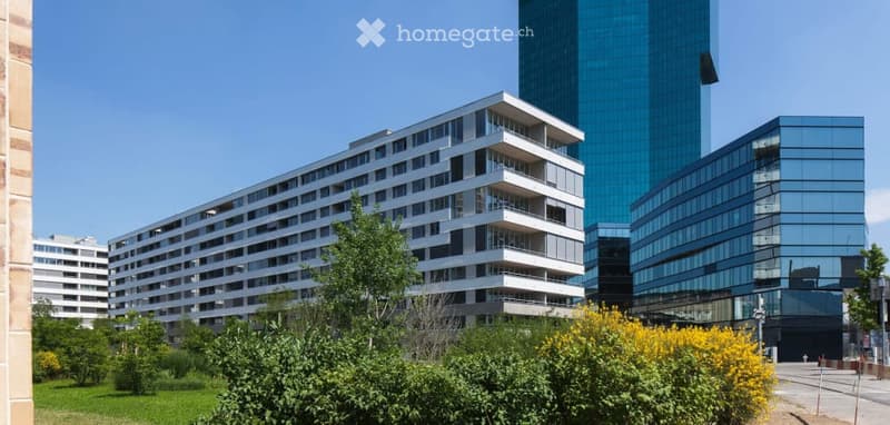 Modern multi-story residential building with balconies, surrounded by greenery and other contemporary structures.