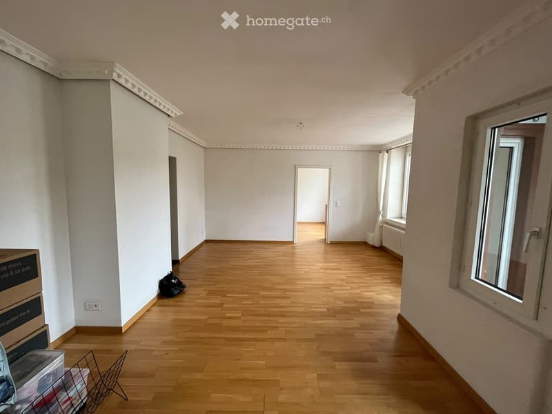 Empty hallway with wooden flooring, white walls, and large windows. No furniture or equipment present.