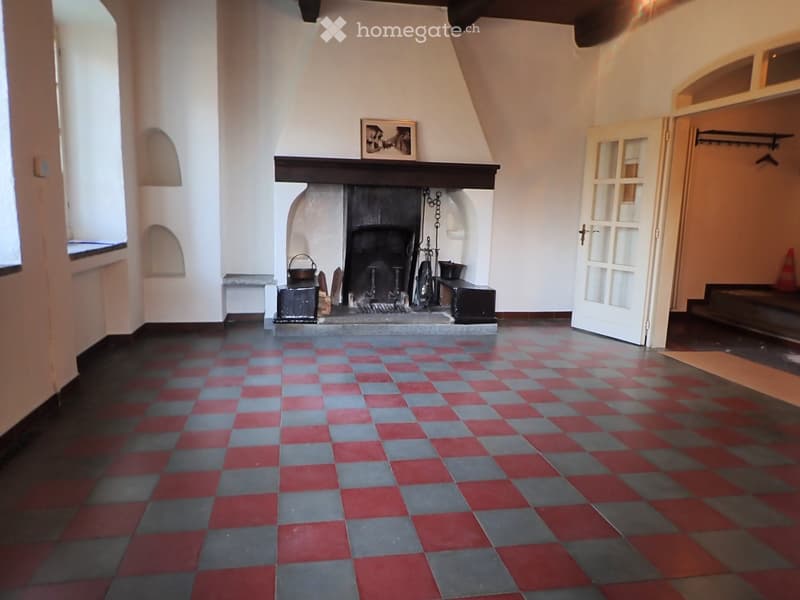 Empty room with a fireplace, checkered floor, and a window on the left side.