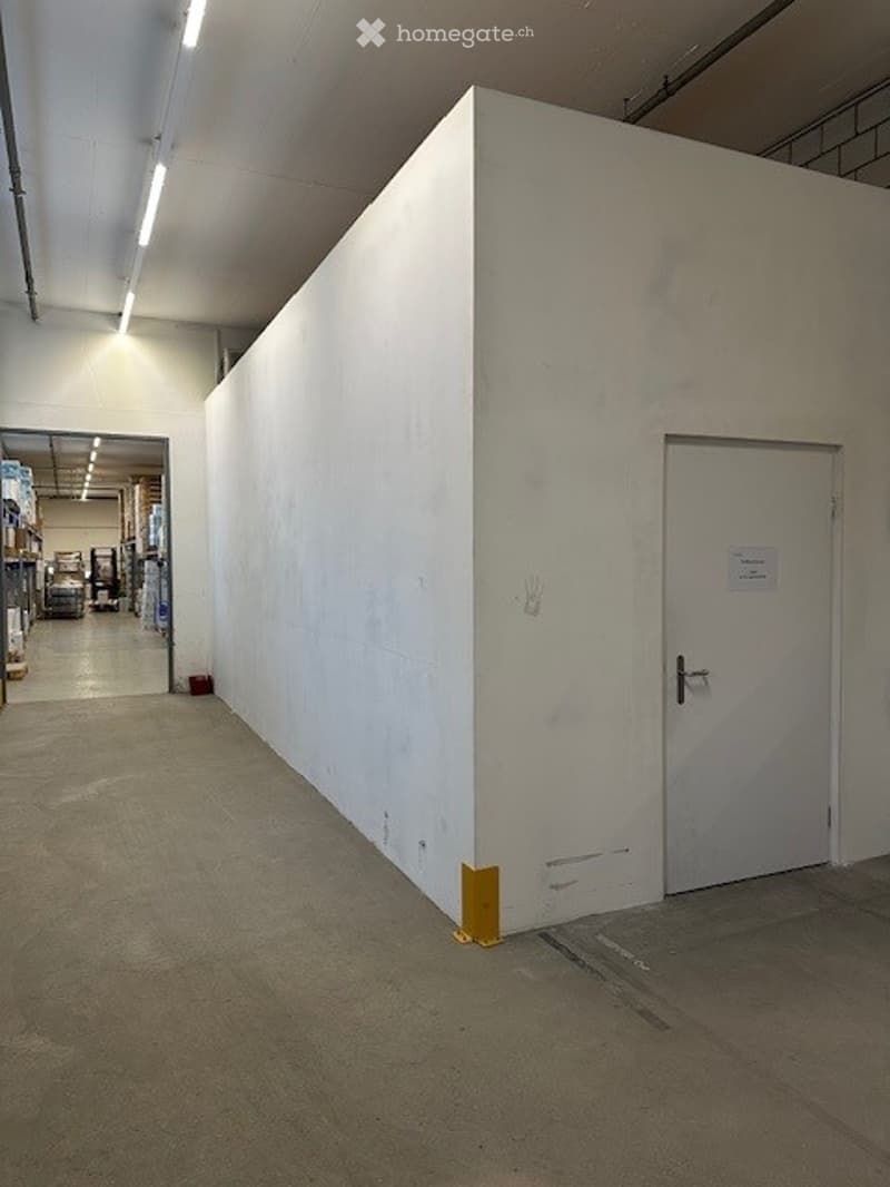Empty storage room, large white wall, two doors, light track ceiling