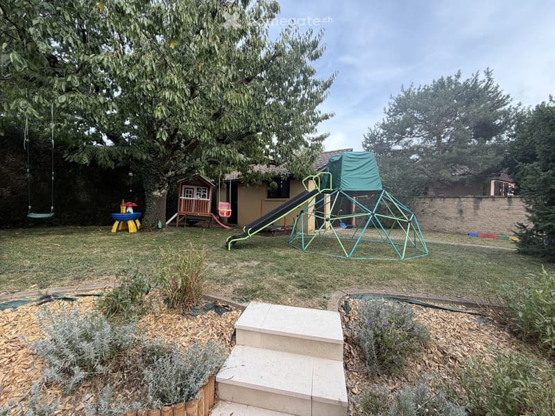 Backyard with a swing, small playhouse, slide, climbing frame, and steps leading up to the house.