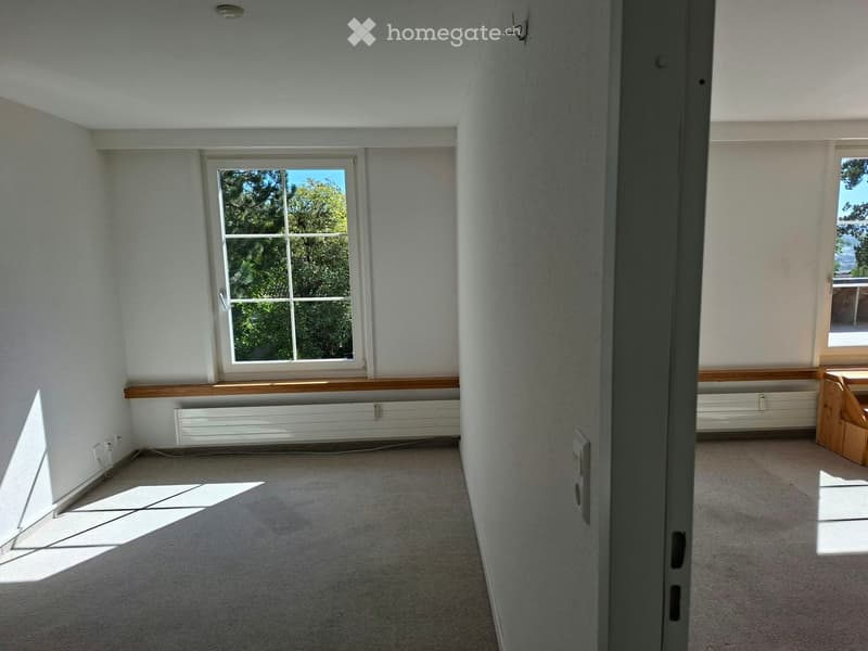 Empty room with carpeted floor, white walls, large windows, and built-in wooden bench seating along one wall.