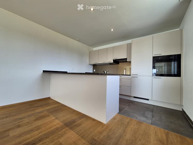 Modern kitchen with white cabinets, a central island, and built-in appliances including an oven and a faucet.