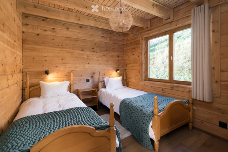Cozy wooden bedroom with two single beds, nightstands, and warm lighting.
