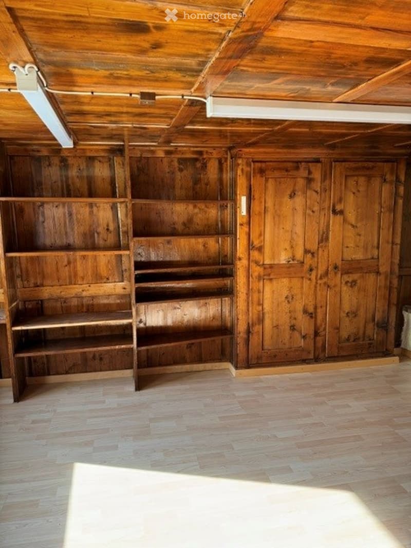 Empty room with wooden walls, shelves, and a wooden floor. No furniture or equipment present.