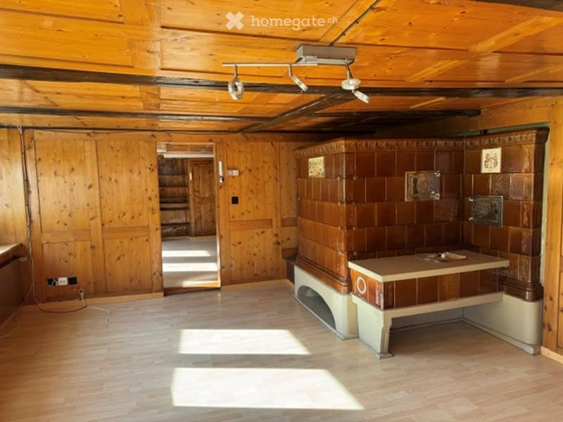 Empty room with wooden walls and ceiling, a small table, and a fireplace. No furniture or equipment visible.