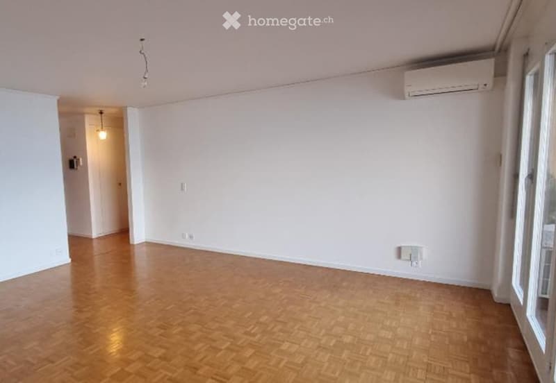 Empty room with wooden flooring, white walls, and large windows. No furniture or equipment present.