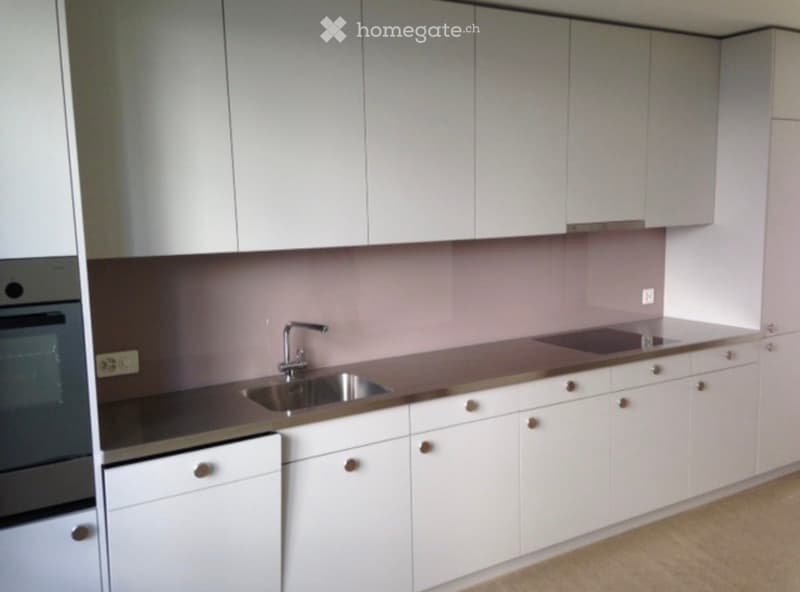 Modern kitchen with white cabinets, stainless steel sink, and built-in oven.