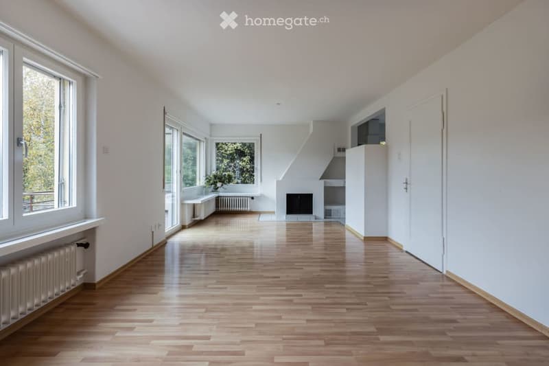 Bright, empty room with wooden flooring, large windows, and white walls. No furniture or equipment present.