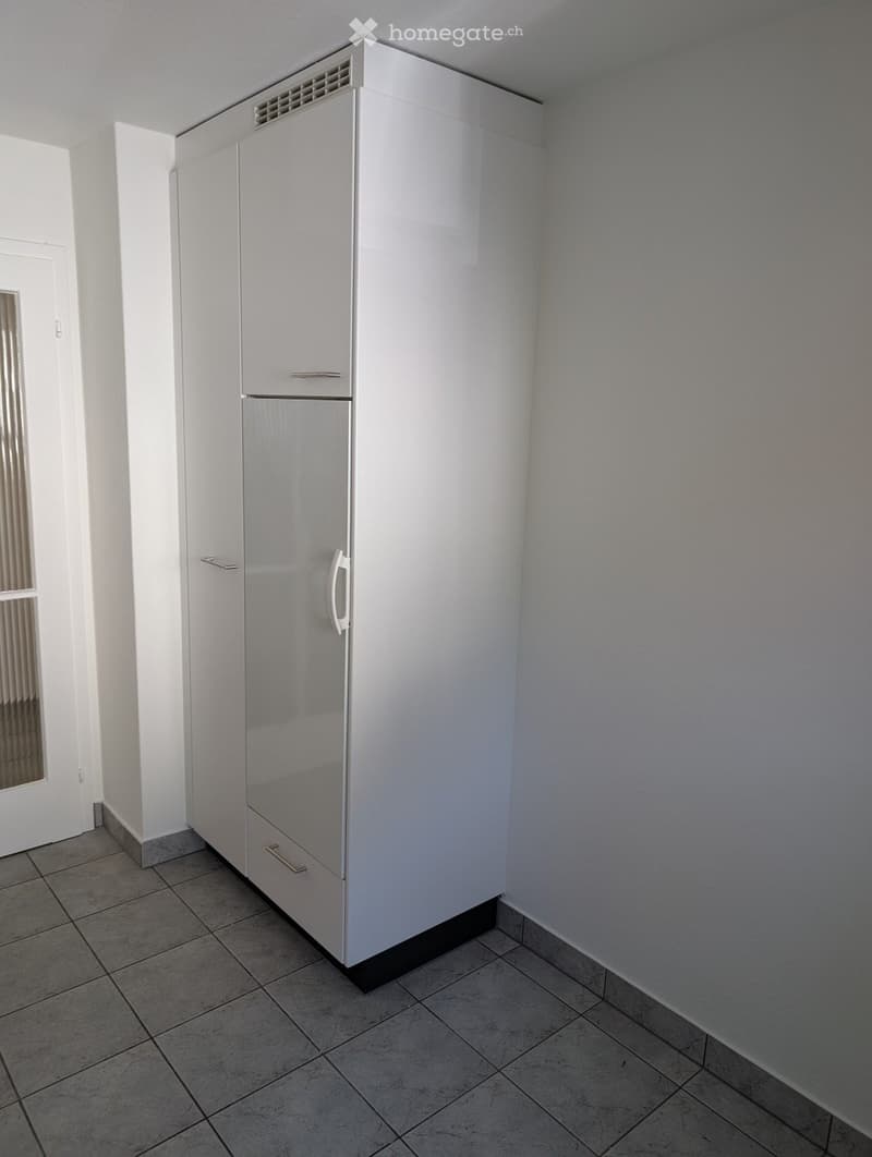 Empty room with tiled floor, white walls, and a white refrigerator with a freezer compartment.