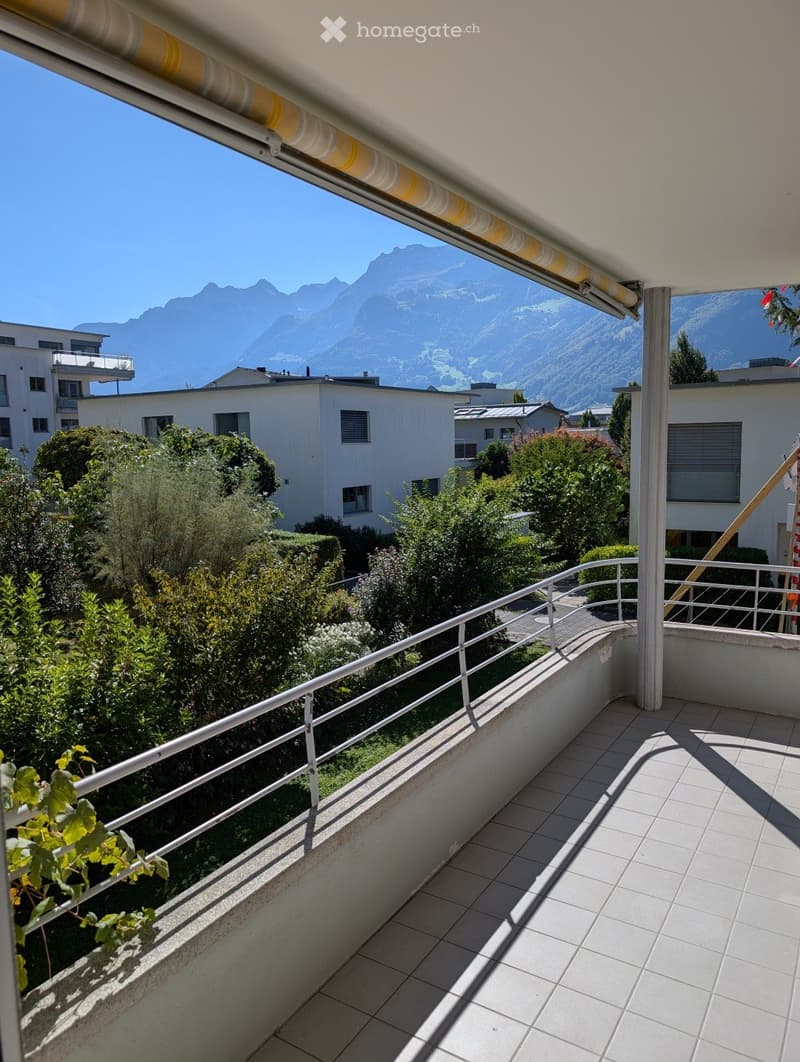 Balcony with tiled floor, metal railing, and scenic mountain view in the background.