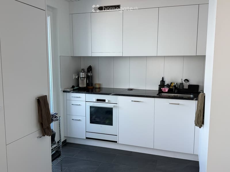 Modern kitchen with white cabinets, stainless steel appliances, and a black countertop.