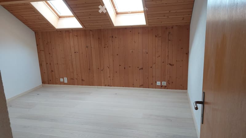 Empty room with wooden walls and floor, skylight windows, and electrical outlets.