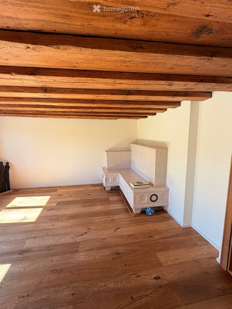 Wooden floor and exposed wooden ceiling with a white bench and a book on top.