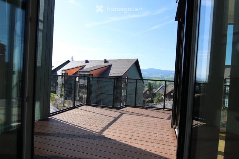 Balcony with wooden decking, black metal railing, and scenic mountain view.
