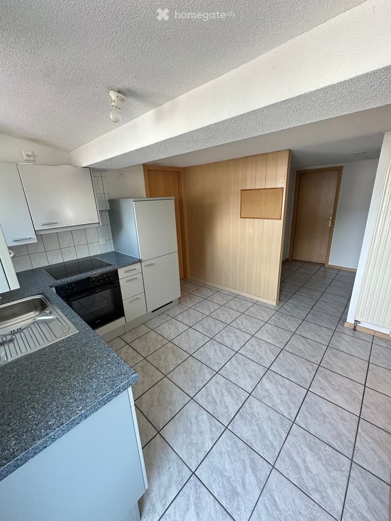 Modern kitchen with white cabinets, stainless steel sink, oven, and refrigerator. Grey tiled floor and granite countertop.