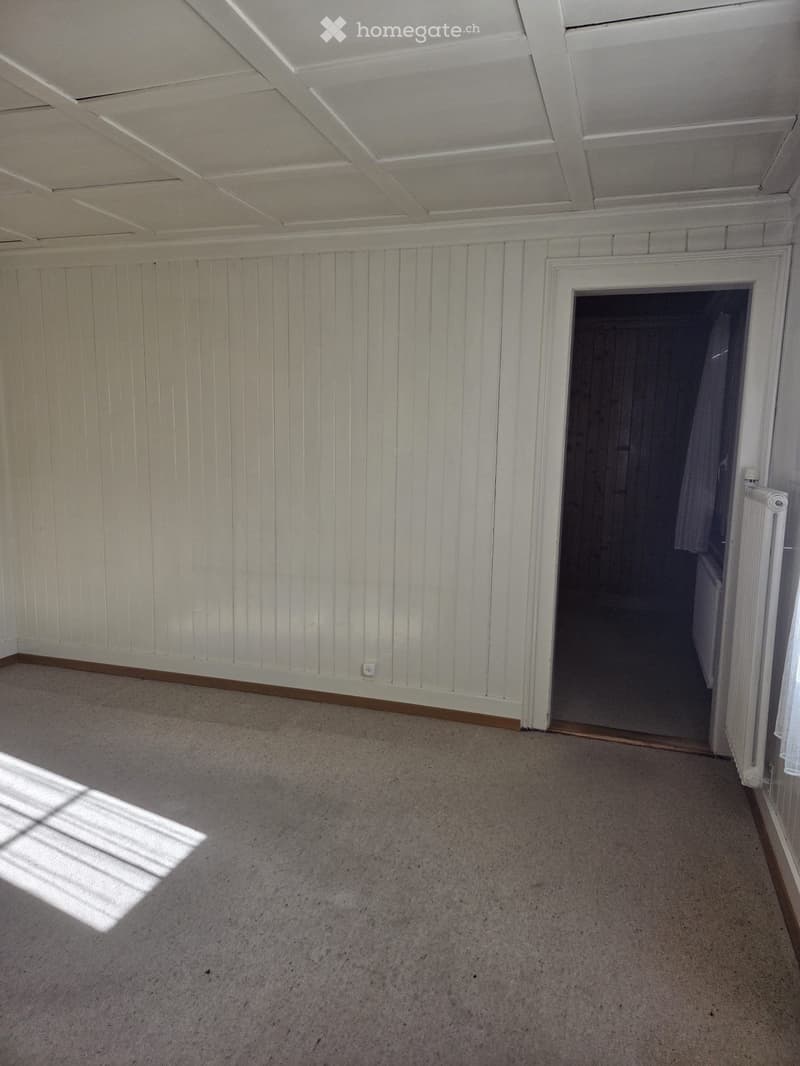 Empty room with light-colored walls, carpeted floor, and a doorway leading to another space. No furniture or equipment is visible.