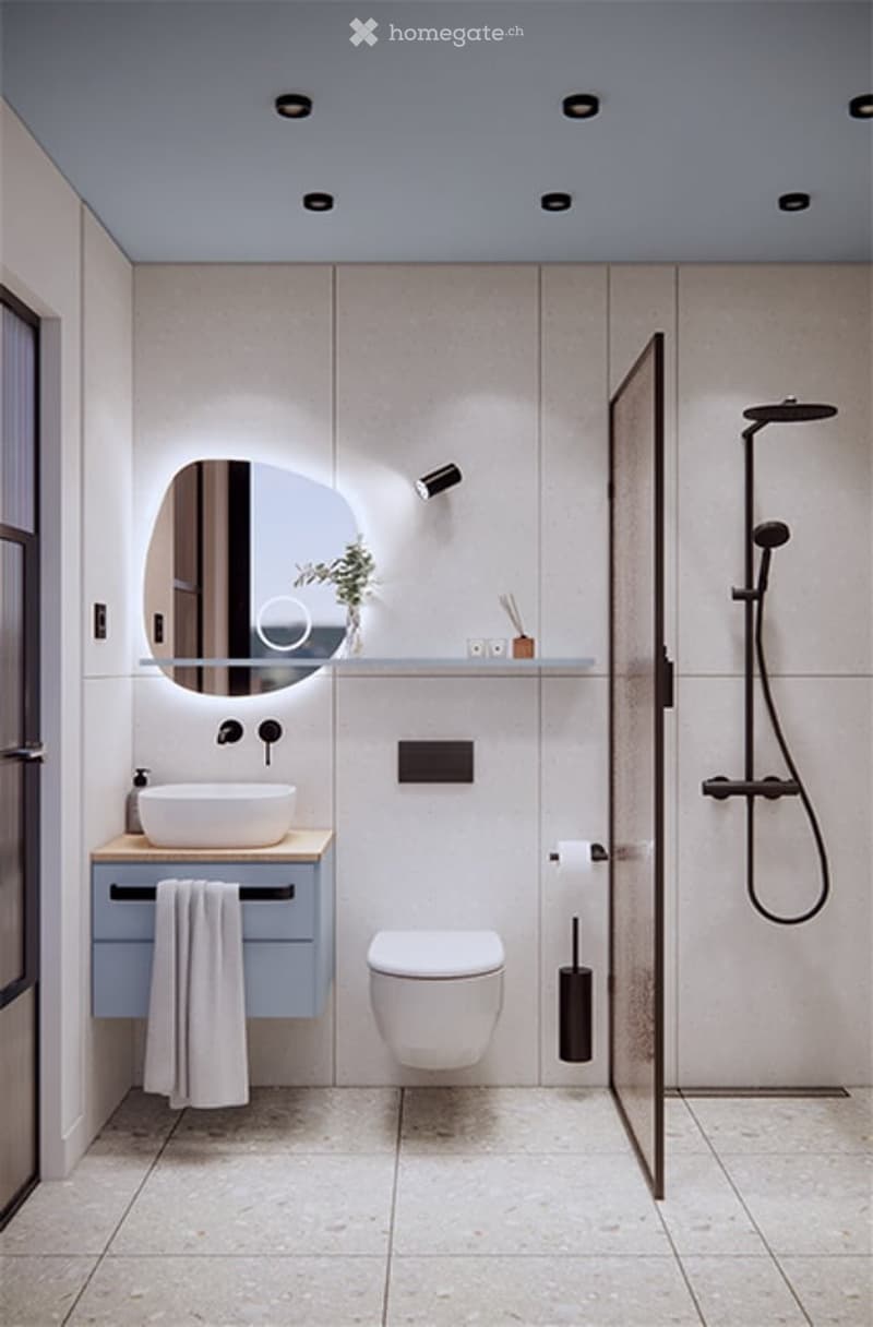Modern bathroom with a white sink, round mirror, toilet, glass-enclosed shower, and a towel hanging on a cabinet.