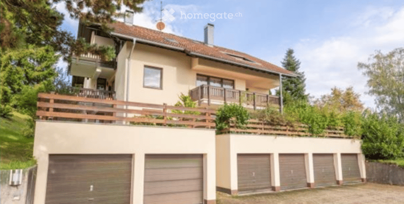 Two-story house with beige exterior, multiple balconies, and attached garage.