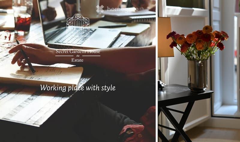 A stylish workspace with a laptop on a table, a vase of orange and red flowers on a small black side table, and a warm lamp providing soft lighting.